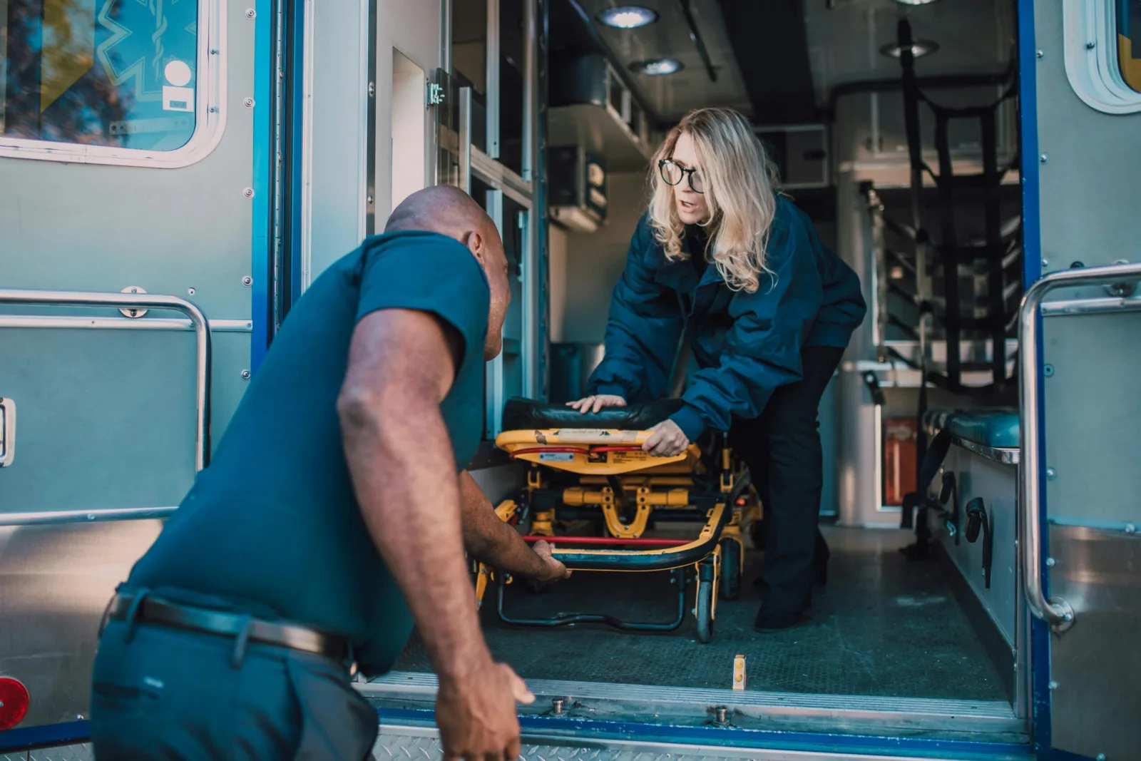 Emergency medical responders preparing an ambulance stretcher